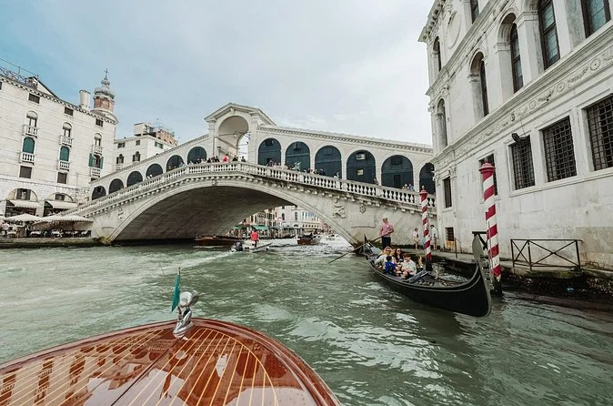 Die Rialto-Brücke vom Bug eines hölzernen Motorboots auf dem Canal Grande aus gesehen
