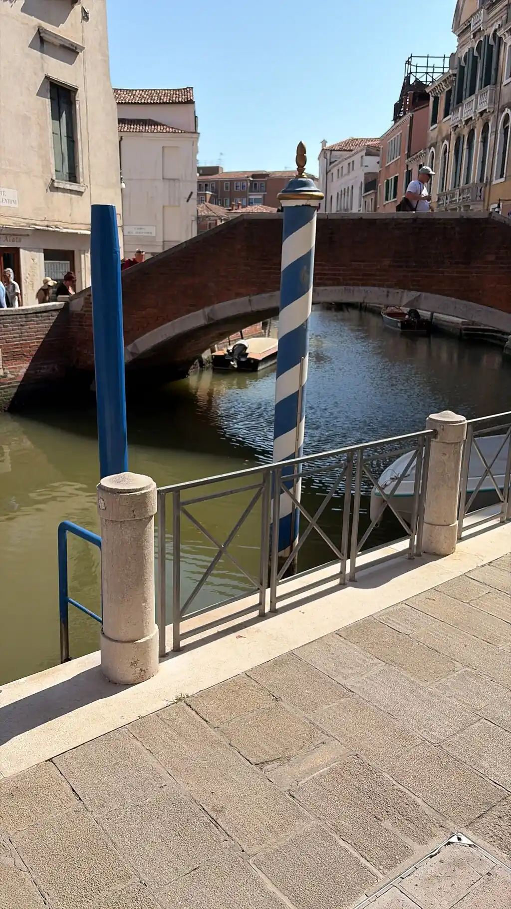 Ein schmaler Kanal zwischen pastellfarbenen Häusern, in der Ferne eine kleine Fußgängerbrücke